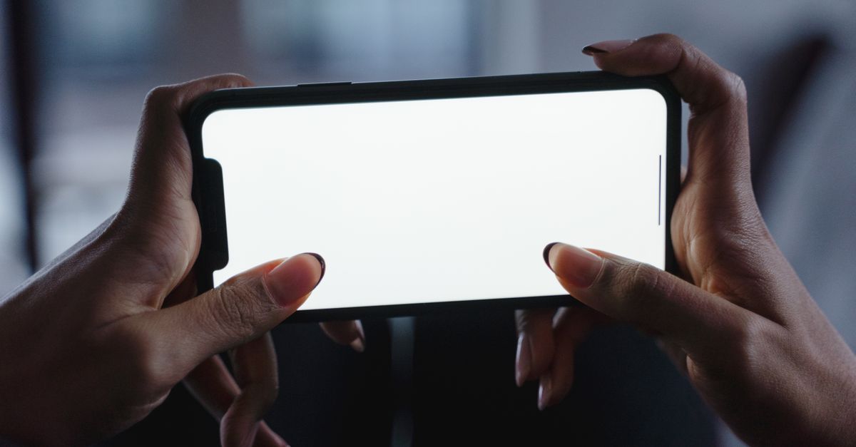 Hands holding a smartphone, checking an earning app before installing it in India