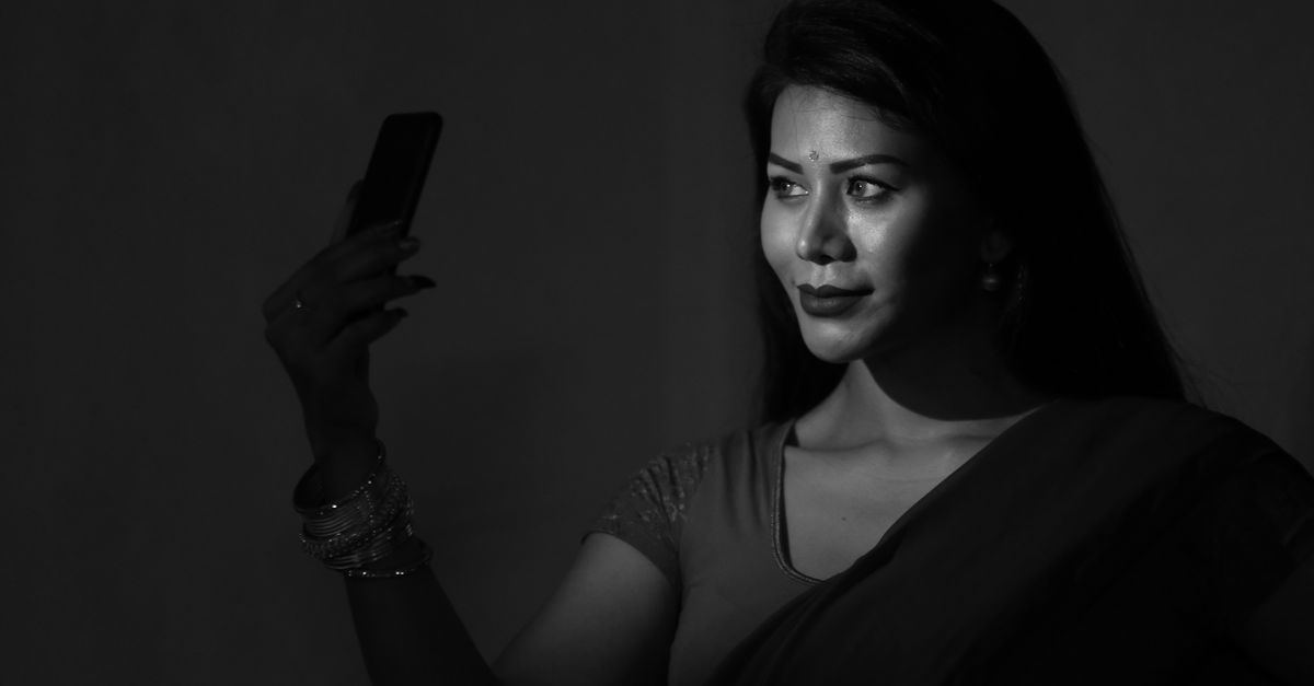 Indian woman looking at her phone at night, deciding whether an earning offer is genuine
