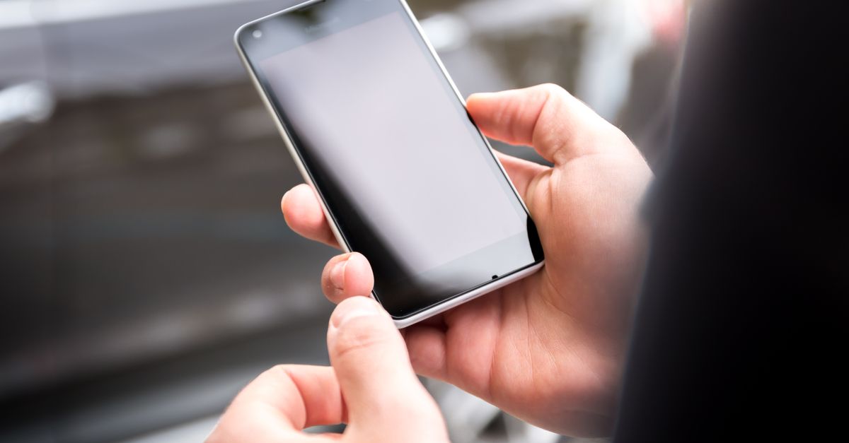 Hand holding a smartphone while verifying an online earning app before signing up