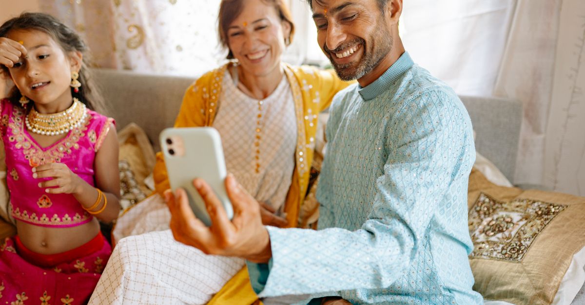 Indian family looking at a phone together, checking whether an earning app is real or fake