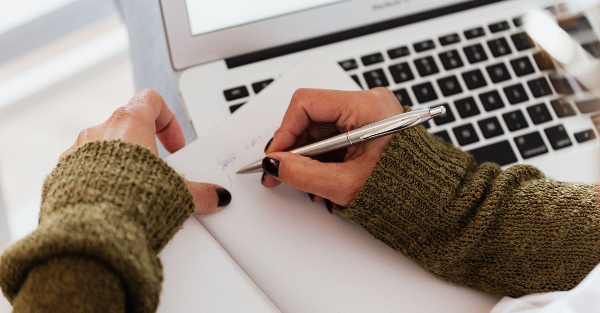 Planning Fiverr gig packages and pricing tiers on paper beside a laptop