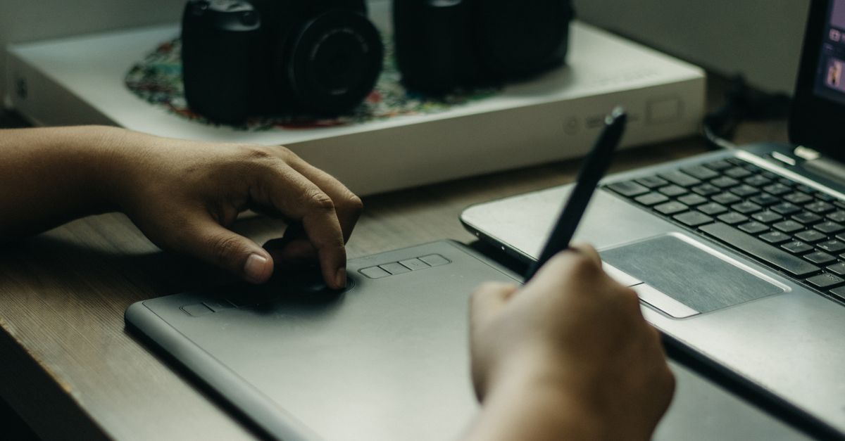 Hand using a drawing tablet to build a Fiverr gig portfolio from India