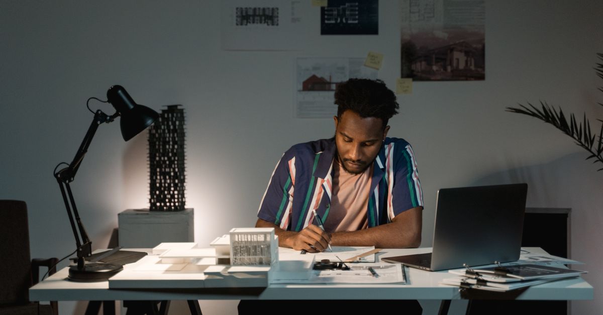 Indian man working on Outlier AI projects at a desk in the evening