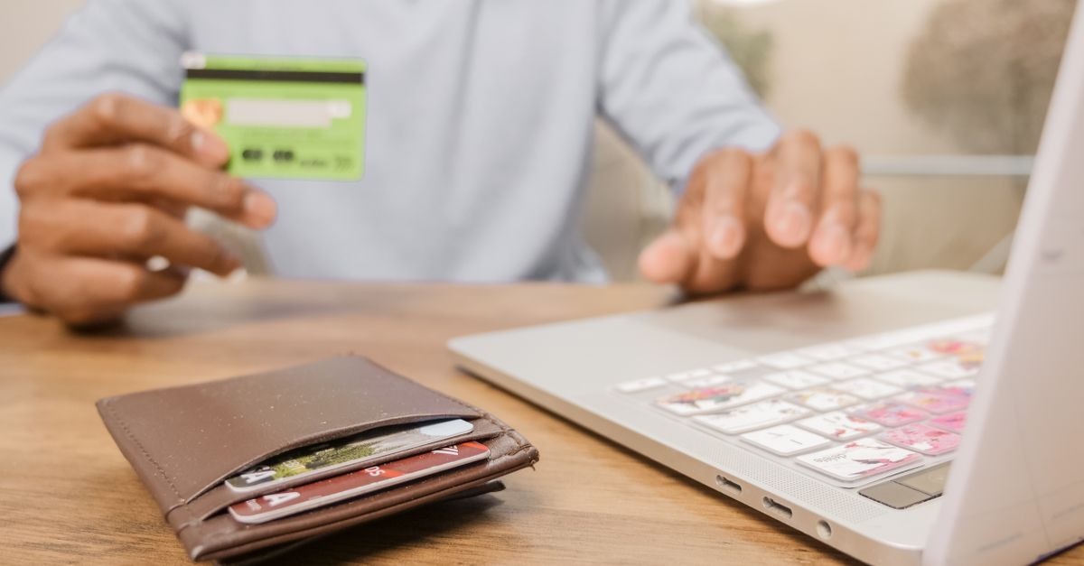 Hands holding a card beside a laptop, comparing PayPal, Payoneer and Wise fees in India