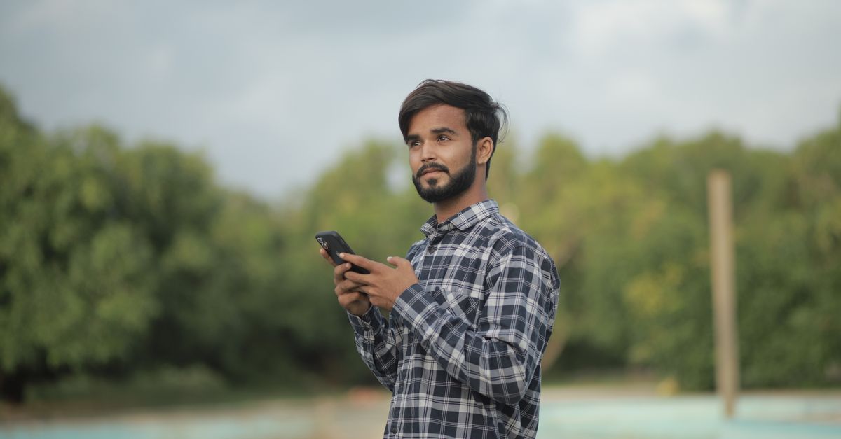 Indian man checking his phone to compare foreign payment providers for freelance income