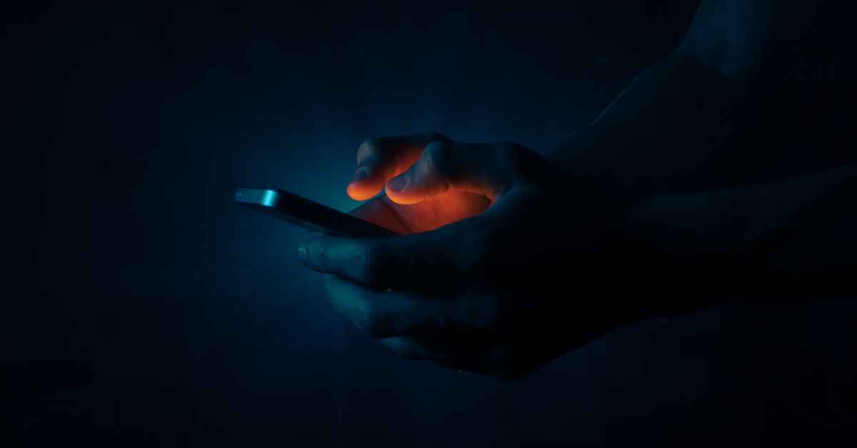 Phone lit in darkness showing a prepaid task scam group on Telegram