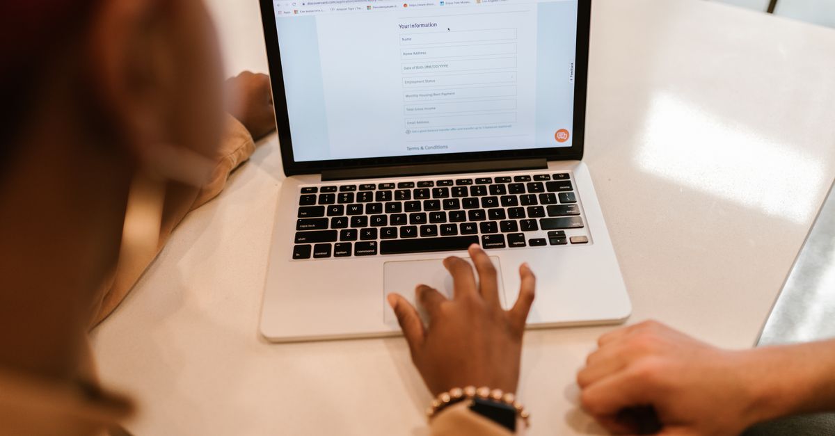 Two people filling in an online application form on a laptop