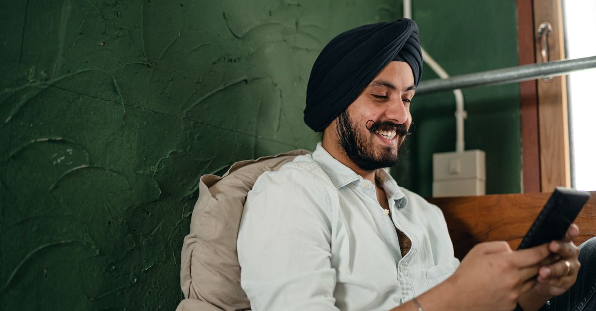 Indian man checking a payment on his phone, choosing between PayPal, Payoneer and Wise