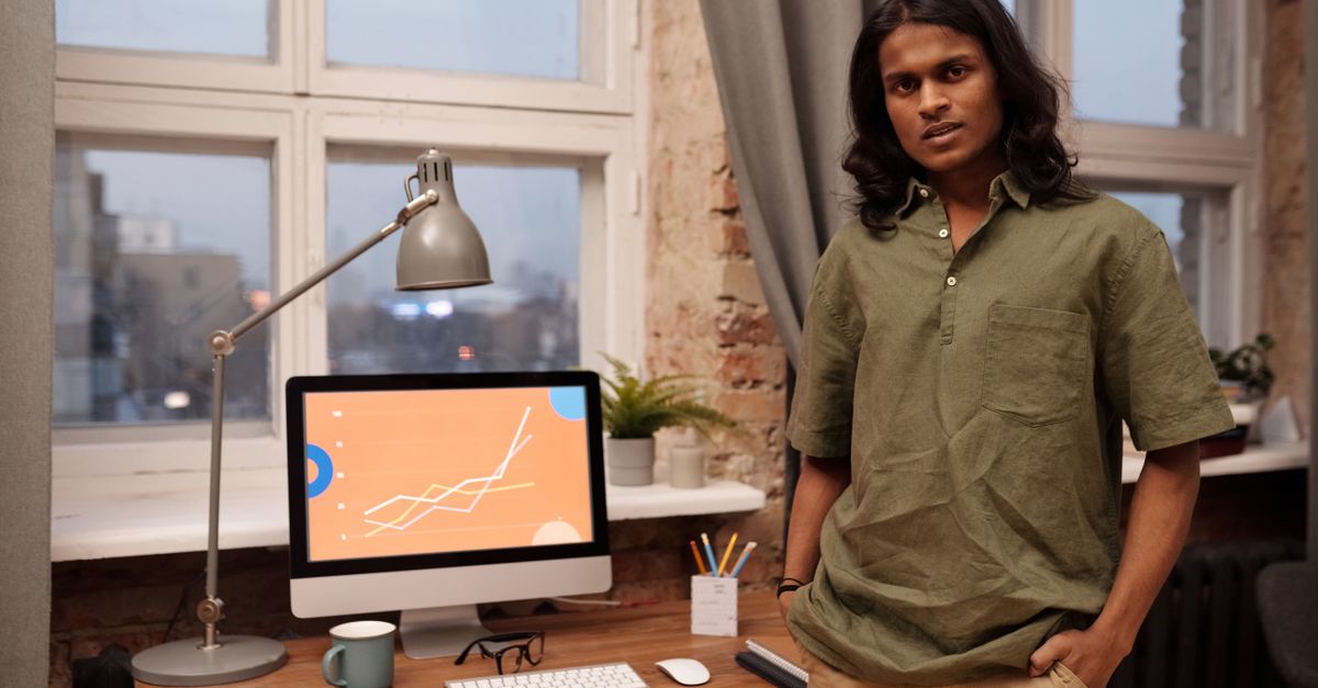 Young man standing beside a desktop computer in a home office