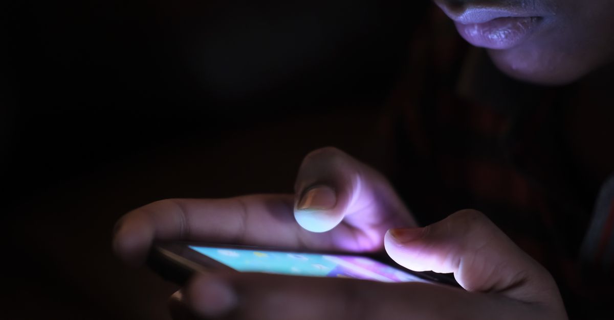 Hands on a glowing phone screen at night, inside a Telegram task scam group in India