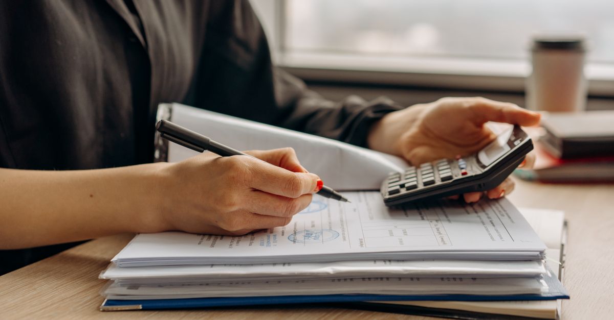 Hands working through figures on a ledger with a calculator