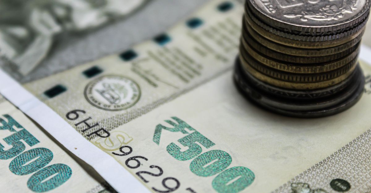 Indian rupee note under a stack of coins, standing for the basic exemption limit