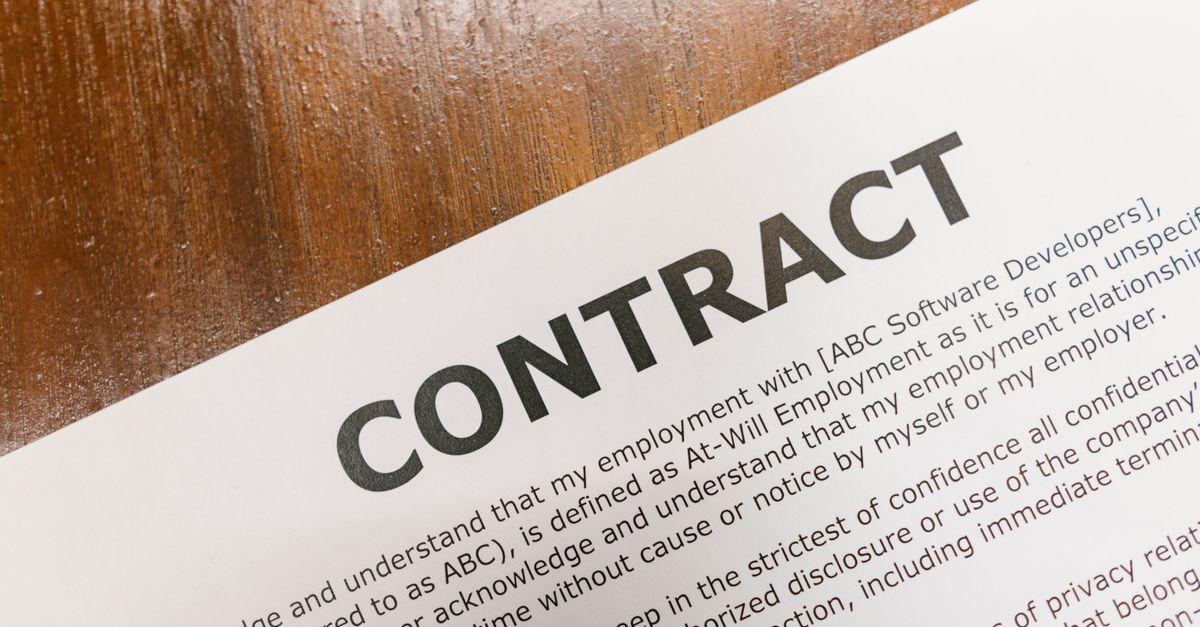 Close up of a printed employment contract document lying on a wooden desk