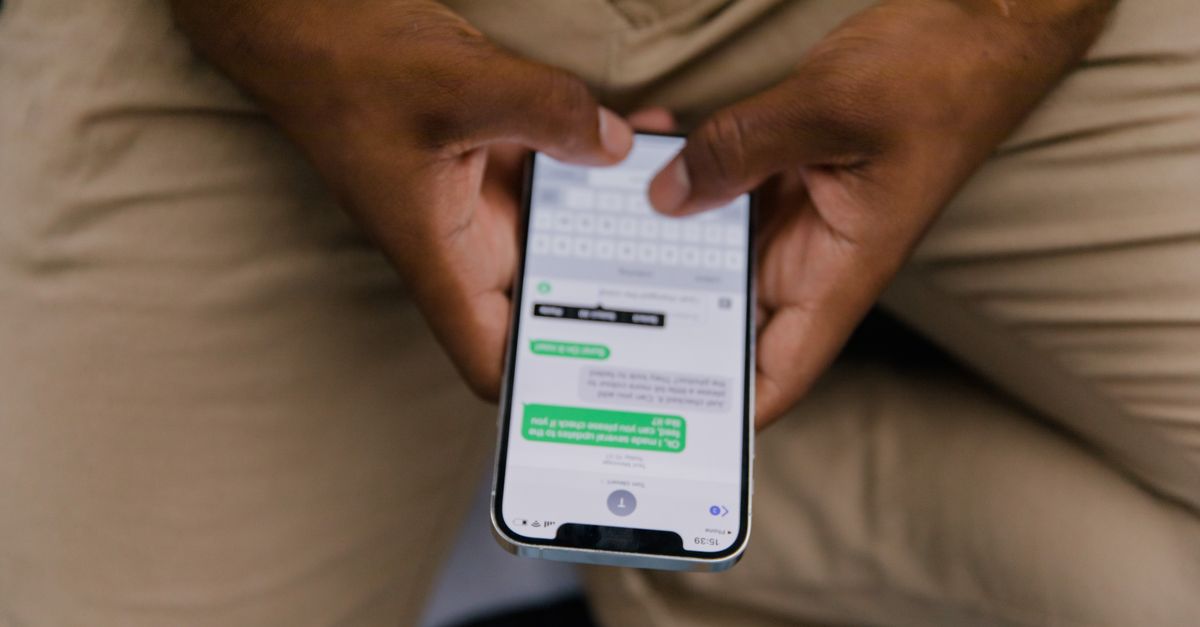 Hands holding a phone showing a chat thread, where task scam instructions arrive