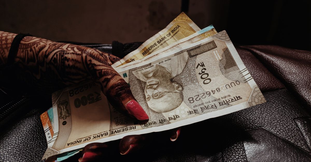 Hands with mehendi counting Indian five hundred rupee notes