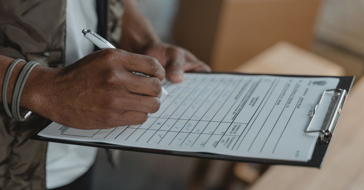 Hands filling in a printed questionnaire on a clipboard