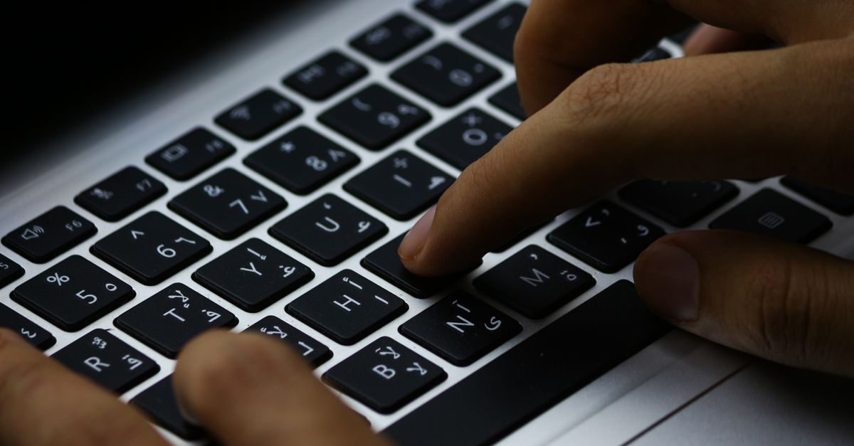 Close view of hands typing on a laptop keyboard, work paid by the hour not the page