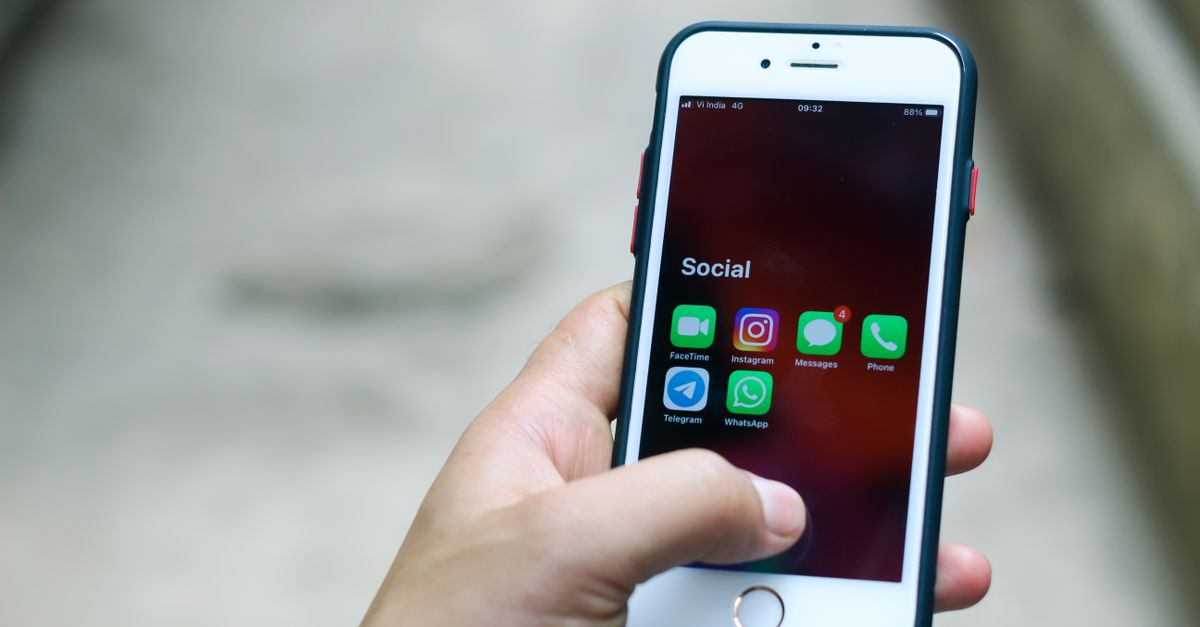Hand holding a phone showing messaging apps, where fake recruiters ask for PAN copies